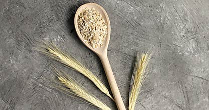 Wooden spoon with oats on table