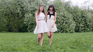 Two happy girls playing in green grass on a background of a flowering tree