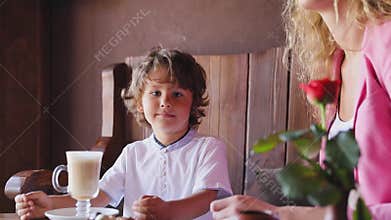 Little boy with cup of cacao at cafe