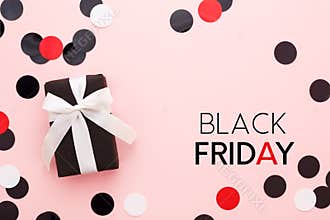 Black friday card with gift box and confetti on pink background.
