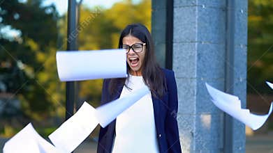 Angry furious female office worker throwing crumpled paper, having nervous breakdown at work, screaming in anger, stress