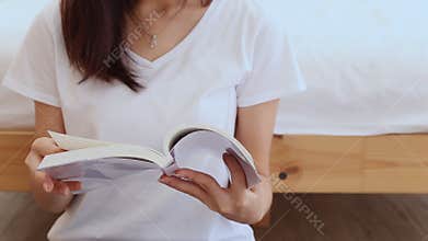 Closeup beautiful asian woman relax sitting reading book on bedroom at home