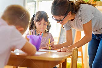 Preschool teacher looking at smart child learning to write and draw