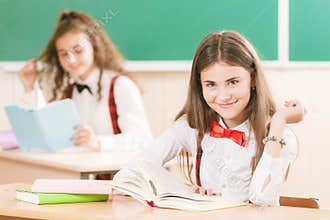 Schoolgirls in school uniforms sit for couples in the classroom. Girls go to school.