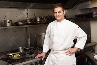 Chef Standing Next To Cooker In Kitchen