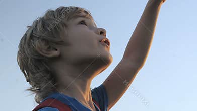 Smiling child looking at blue sky.