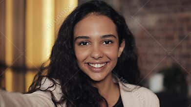 Attractive young woman video chatting, spying. Woman waving at the camera while sitting in the cozy cafe. close up