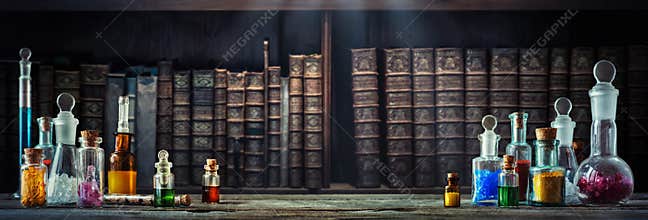 Vintage medications in small bottles on wood desk and old book background. Old medical, chemistry and pharmacy history concept