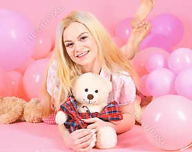 Young woman on bed hugging teddy bear. Birthday girl concept. Blonde on smiling face relaxing with teddy bear toy. Woman