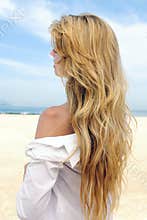 Elegant woman with long blond hair at the beach