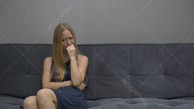 A young woman sits on a couch and feels frustrated, depressed and fear. Copy space on the right side