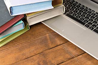 Books and laptop on wooden table. The concept of learning from books or from the Internet