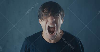 Portrait of angry hipster man in black cap screaming with agression. Threat of violence.