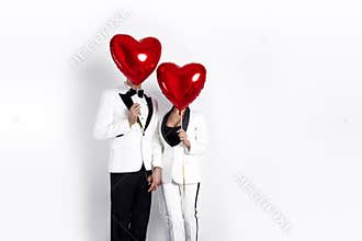 Happy beautiful couple posing on white background and holding balloons heart. Valentine`s day.