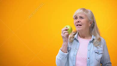 Joyful aged woman enjoying taste of fresh crispy apple, oral care, orthodontics