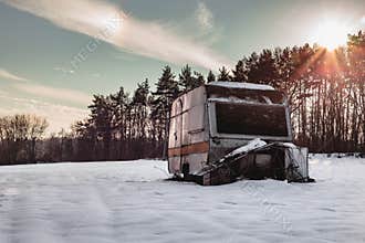 Beautiful photo of old and abandoned caravan in the middle of snow covered meadow in Winter time. Illuminated Caravan campervan