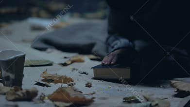 Homeless refugee praying and kissing bible, hope for better life, asylum seeker
