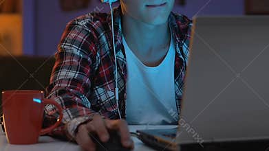 Addicted male teenager in headset playing online game at night, nervous behavior