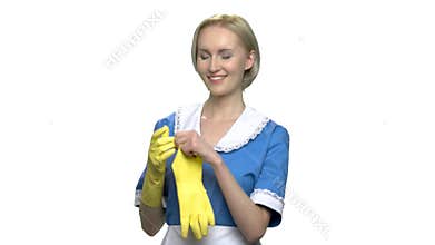 Young smiling chambermaid puts on yellow gloves.