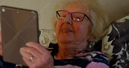 Close-up of senior woman using digital tablet on bed in bedroom 4k