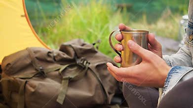 Man hands holding iron mug at travel tent on field