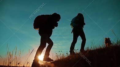 Teamwork. Two hikers enjoying sunrise walking from top of a mountain and dog. slow motion video. Two hikers with
