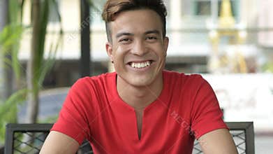 Face of happy young Asian man smiling at the coffee shop outdoors