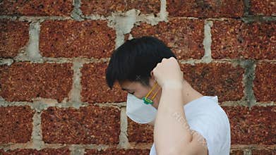 Asia man Stay beside and wear N95 mask for protect bad pollution PM2.5 dust with brick background