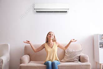 Young woman relaxing under air conditioner