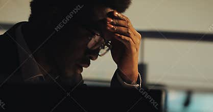 Tired young black businessman working with documents at night office. Portrait of handsome business man analyzing papers