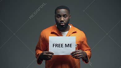 African-american prisoner holding Free me sign in cell, innocent asking for help
