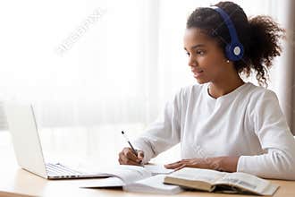 African American teen girl wearing headphones learning language online