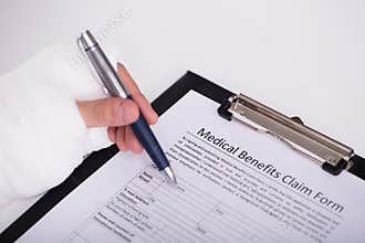 Person With Fractured Hand Filling Medical Benefit Claim Form