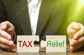 A businessman puts two puzzles with the words Tax and Relief. The concept of reducing the debt burden on business and local