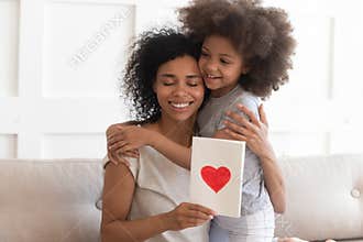 African mum hugging daughter holding greeting card on mothers day