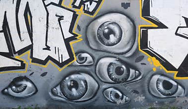 Graffiti art in the city street showing many painted eyes on the concrete gray wall as background.
