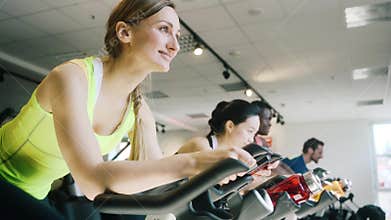 Side view of a beautiful woman smiling while cycling at the gym