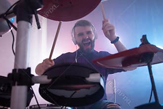 Music, drums, hobby and interests concept - Emotional drummer plays the drums. Photo with lighting motion effect