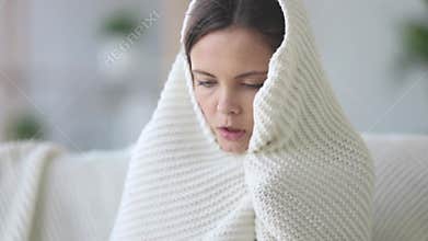 Covered with plaid young woman freezing feeling cold at home