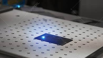 Laser engraving machining working. Laser engraving machining at work. Beam of laser writing picture on plywood