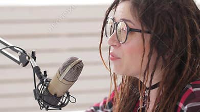 Podcasting and radio concept. Radio host young woman in the studio in front of a microphone