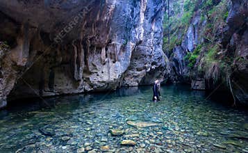 Female looks up in awe admiring the canyon walls and caves high above her