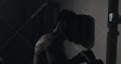 Silhouette boxer man hits punching bag in dark gym. Close up fighter workout. Male boxer exercising in dark. Kickboxer