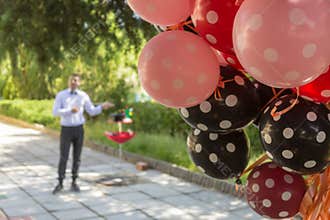 Performing of a magician through an outdoor birthday party with balloons