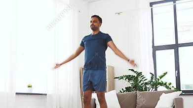 Indian man doing jumping jack exercise at home