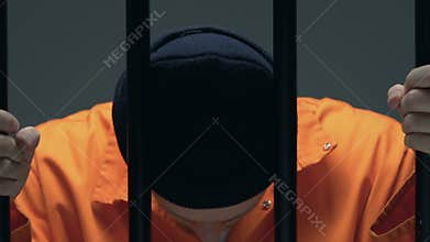 Desperate prisoner with scars on face holding cell bars, death penalty waiting