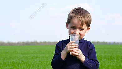 Happy child drinks fruit juice from a glass in nature. Healthy and proper nutrition of children. Environmentally