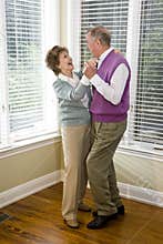 Loving senior couple dancing in living room