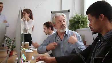 Older male mentor helping teaching new employee training intern