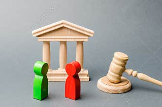 Wooden figures of people standing near the judge`s gavel. Litigation. Business rivals. Conflict of interest. Law and justice. The